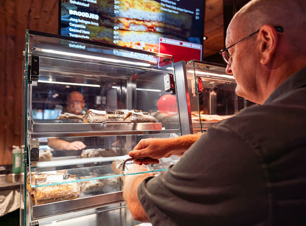 Man pakt snack uit warmhoudvitrine