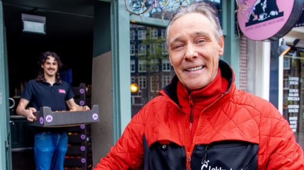 Lachende man in Lekkerland jas met blije klant