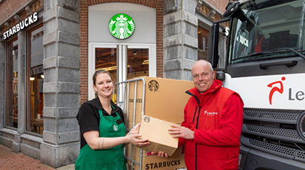 Lekkerland chauffeur overhandigt doos aan Starbucks medewerker