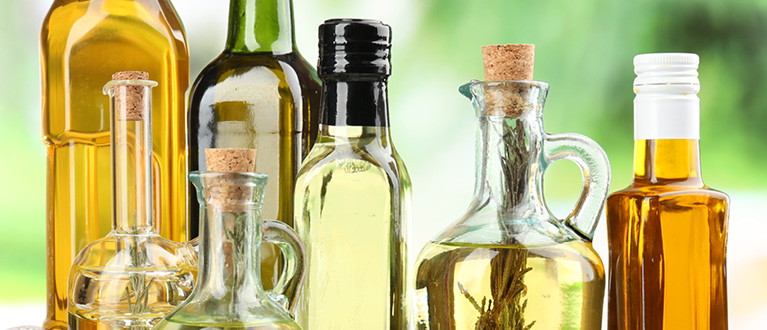 Flessen olijfolie naast elkaar met groene achtergrond
