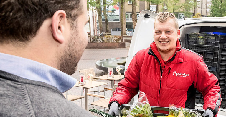 Medewerker Lekkerland die eten in krat brengt